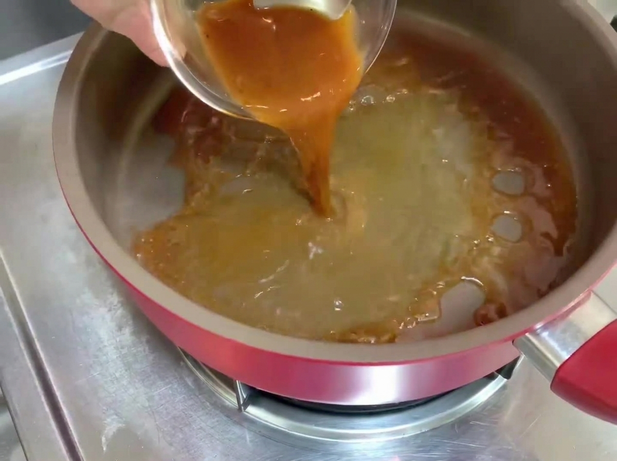Sauce au poivre noir versée dans une poêle chaude, créant un liquide frémissant.
