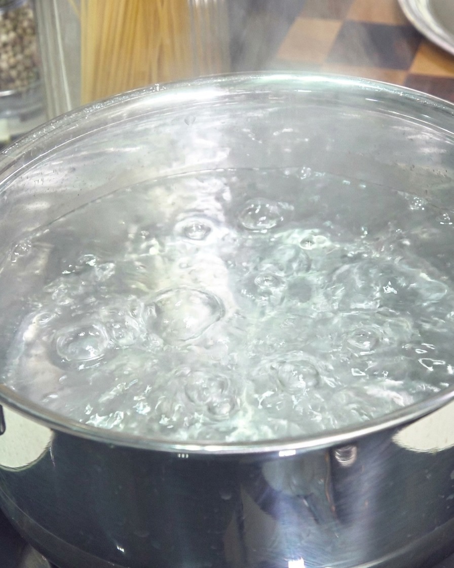 Une casserole en acier inoxydable remplie deau bouillante à gros bouillons.