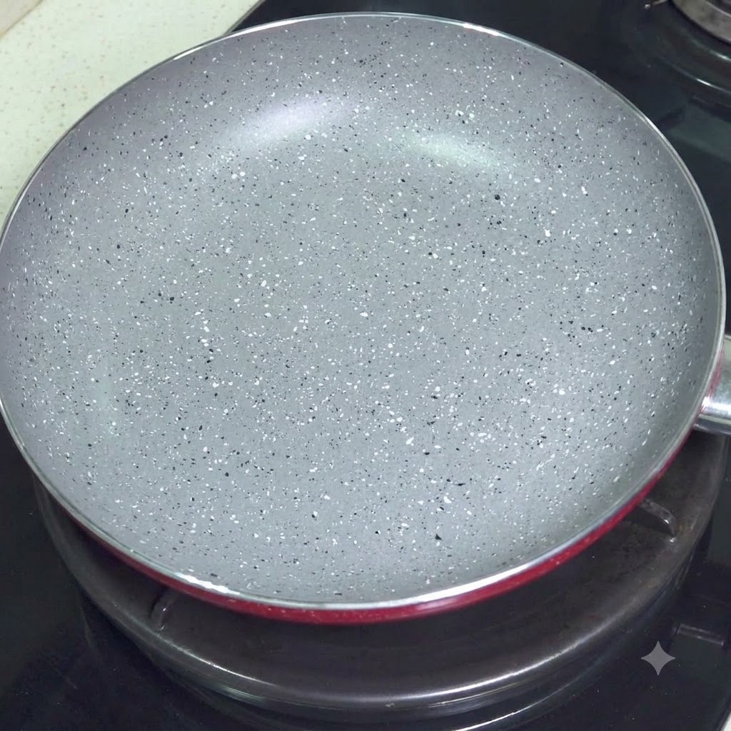 Une poêle antiadhésive grise vide posée sur une plaque de cuisson.