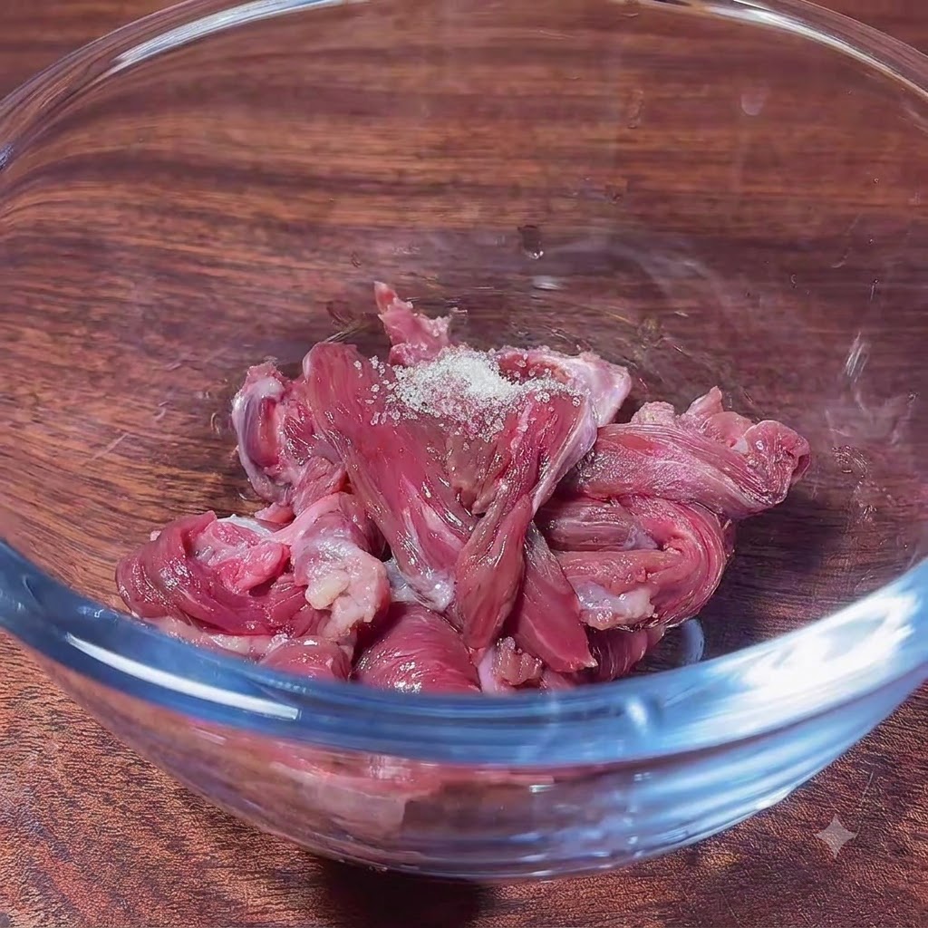 Tranches de bœuf cru dans un bol en verre, prêtes à être mélangées avec la marinade.