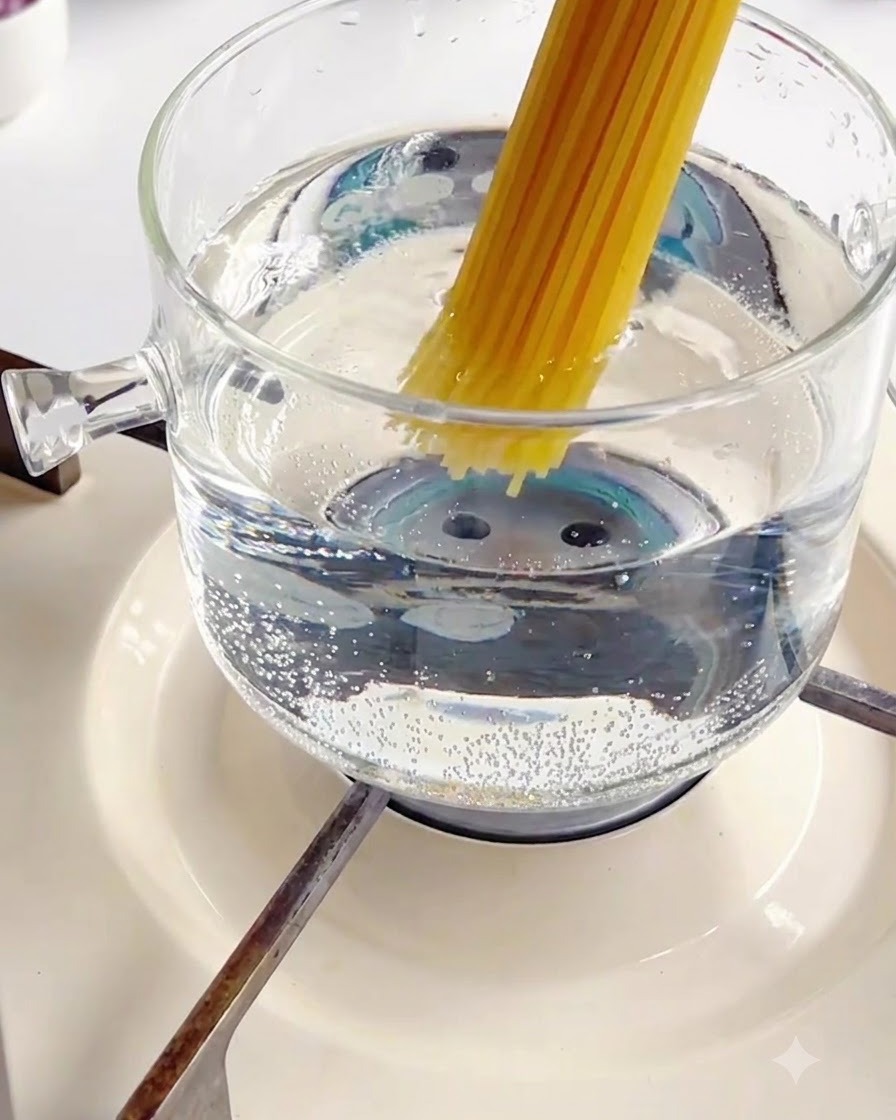 Insertion dun paquet de spaghettis secs dans une casserole en verre bouillante.