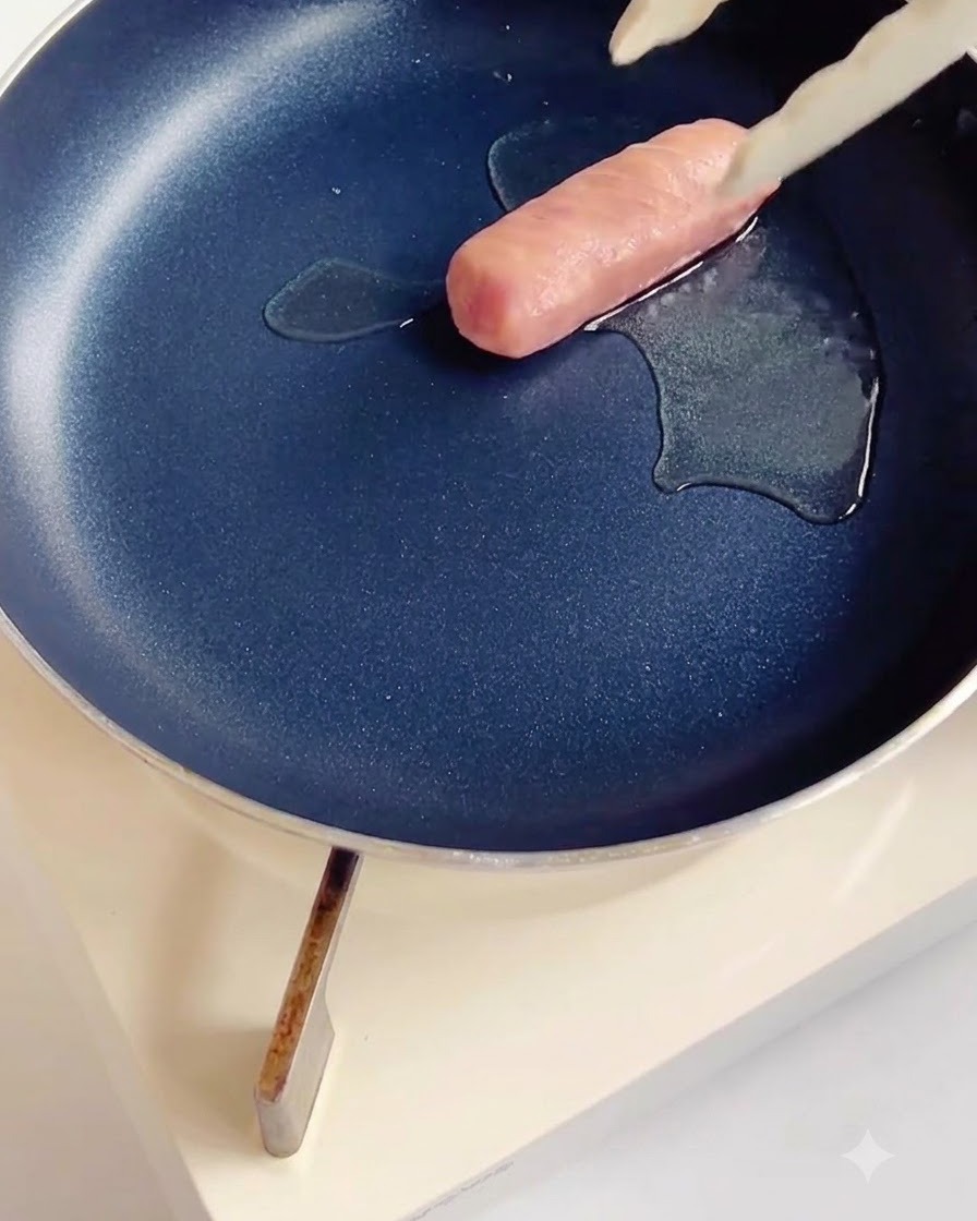 Saucisses quadrillées cuisant dans une poêle antiadhésive foncée avec un peu dhuile.
