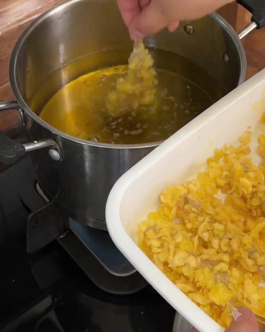 Une crevette généreusement enrobée abaissée dans de lhuile chaude dans une casserole en métal.
