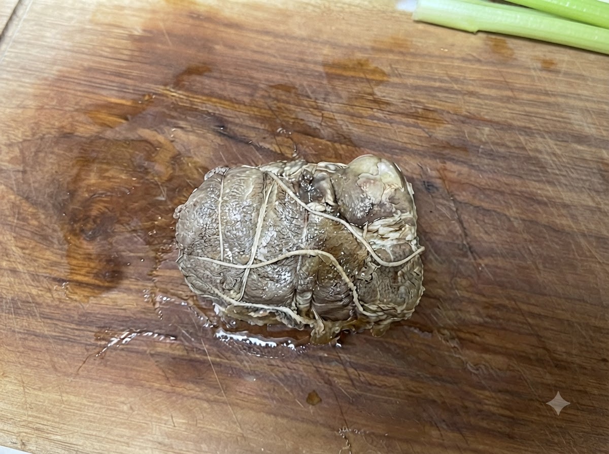 Porc chashu roulé et ficelé reposant sur une planche à découper en bois avant dêtre tranché.