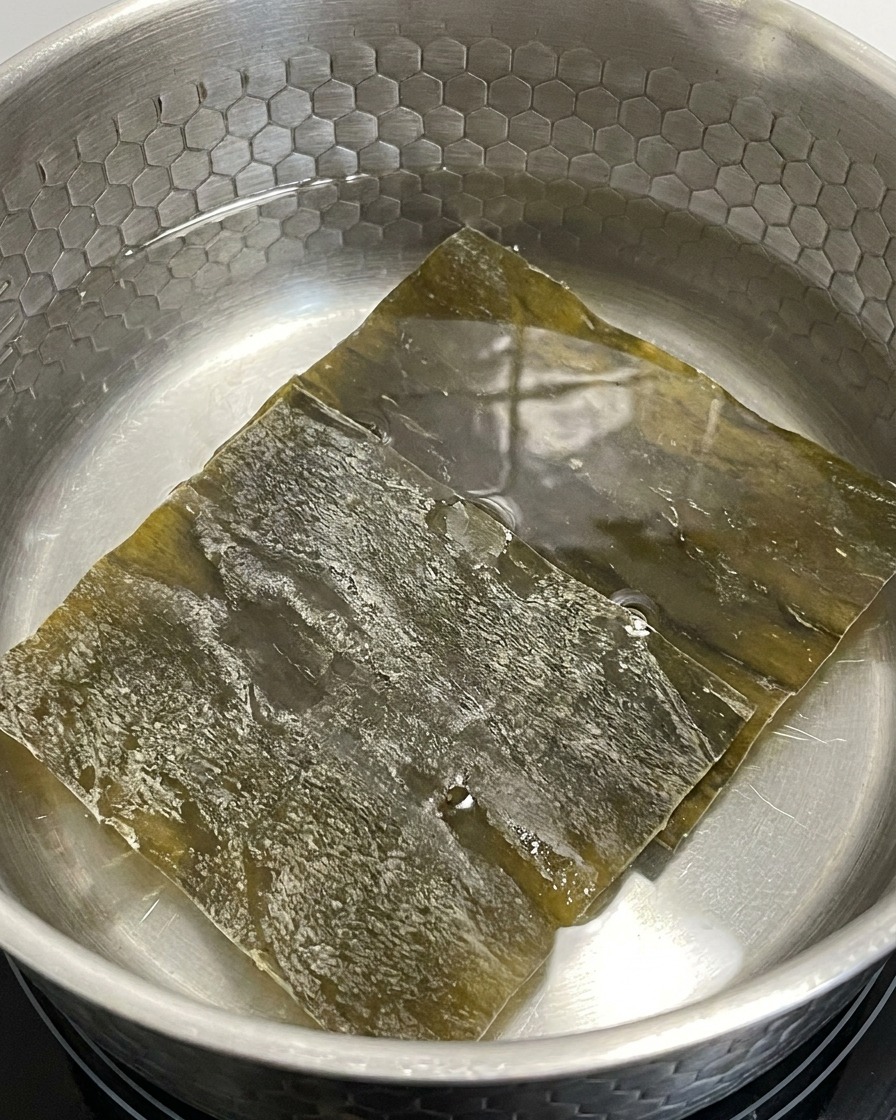 Morceaux de kelp séché trempant dans une casserole deau à feu doux.