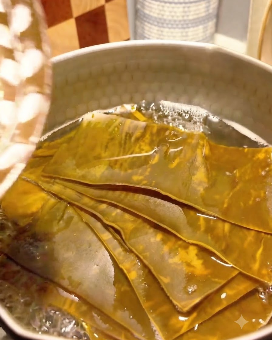 Flocons de bonito ajoutés au bouillon de kelp frémissant dans une casserole.