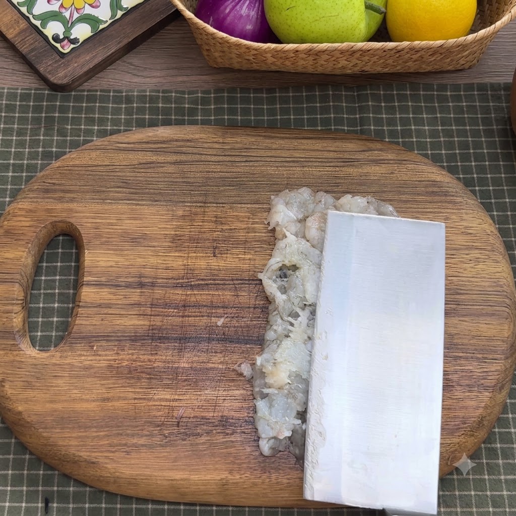 Chair de crevette hachée dans un bol mélangeur en métal avec des condiments, des blancs dœufs, de la fécule et de leau.