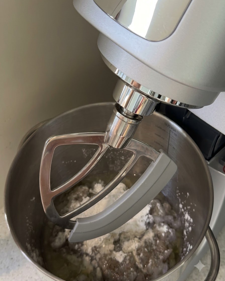 Un robot sur socle muni dune feuille mélangeant les crevettes hachées, la fécule et les liquides dans un bol en inox.