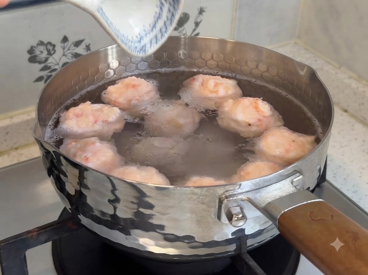 De belles boulettes de crevettes maison en train de frémir dans une casserole deau chaude sur la cuisinière.