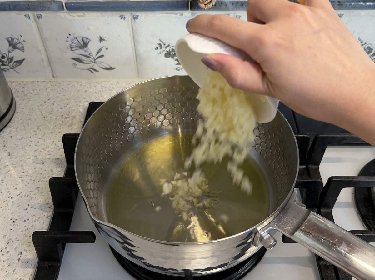 Ail haché et tomates en dés ajoutés dans de lhuile chaude dans une casserole pour être saisis.