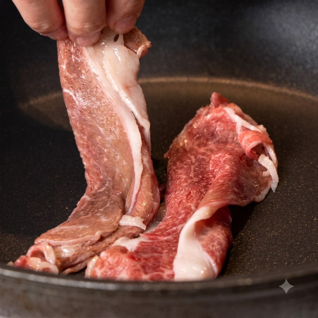 Des tranches de paleron de bœuf wagyu déposées dans une poêle antiadhésive sèche et chauffée.