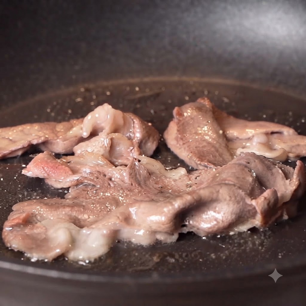 Du poivre noir et du sel saupoudrés sur des tranches de bœuf saisies en train de cuire dans une poêle.
