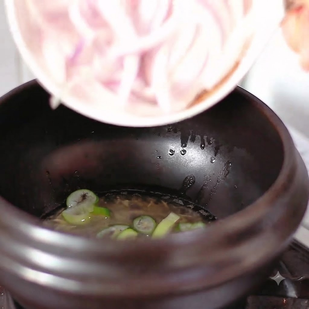 Oignons rouges émincés versés dans la marmite contenant lhuile et les oignons verts.