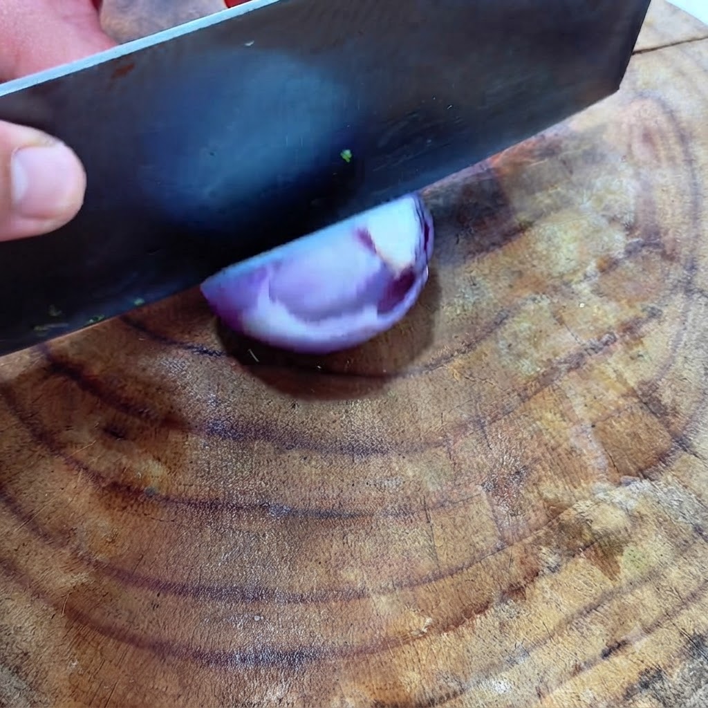 Un grand hachoir coupant en dés une moitié doignon rouge sur une surface en bois.