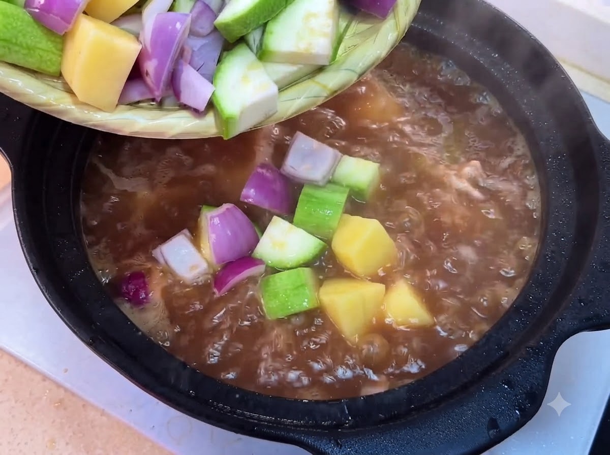 Des courgettes, pommes de terre, oignons, pousses de soja, champignons et tofu hachés versés dun plateau dans la casserole bouillante.