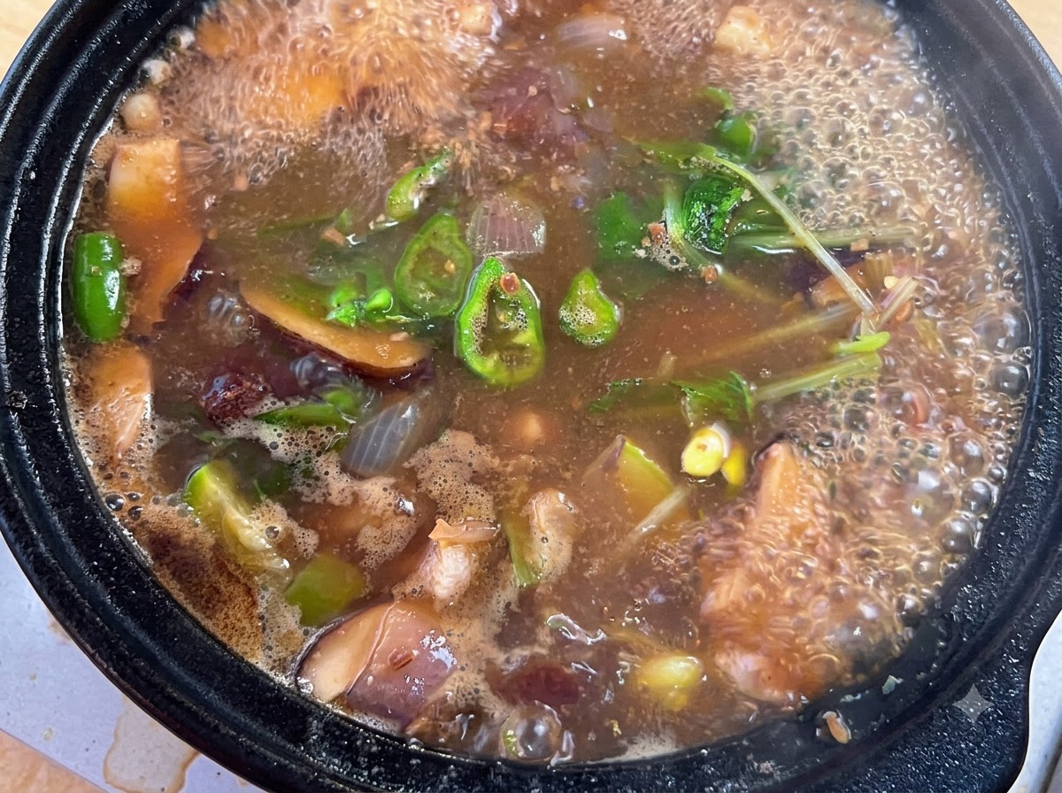 De la poudre dassaisonnement de bœuf, de la poudre de piment et des oignons verts hachés ajoutés dans la casserole de ragoût bouillonnante.