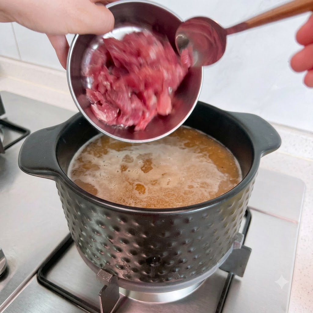 Morceaux de porc cru versés dun bol en métal dans la soupe bouillante.