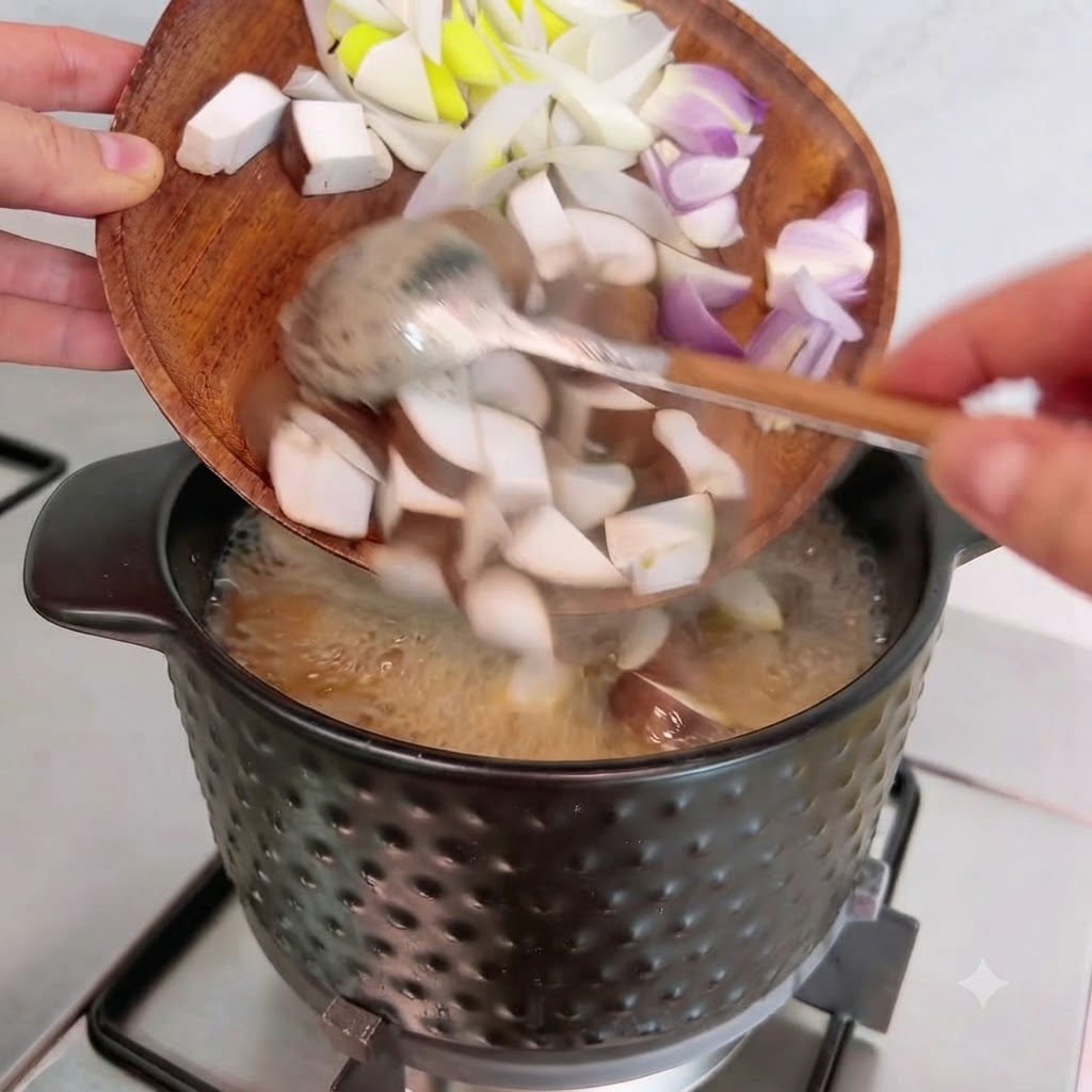Dés de champignons shiitake, oignons et cébettes versés dune assiette en bois dans la casserole.