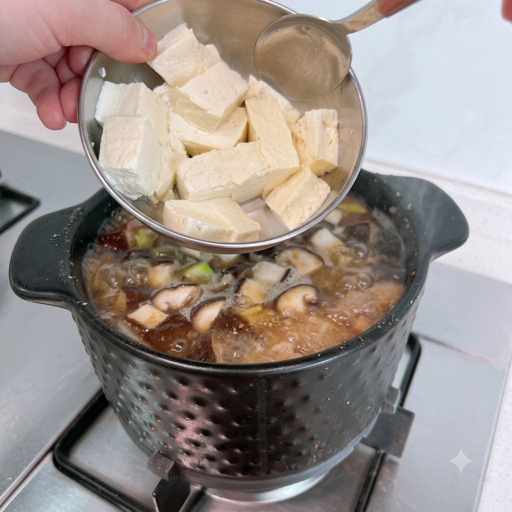 Tranches de tofu blanc ajoutées délicatement dans le ragoût frémissant.