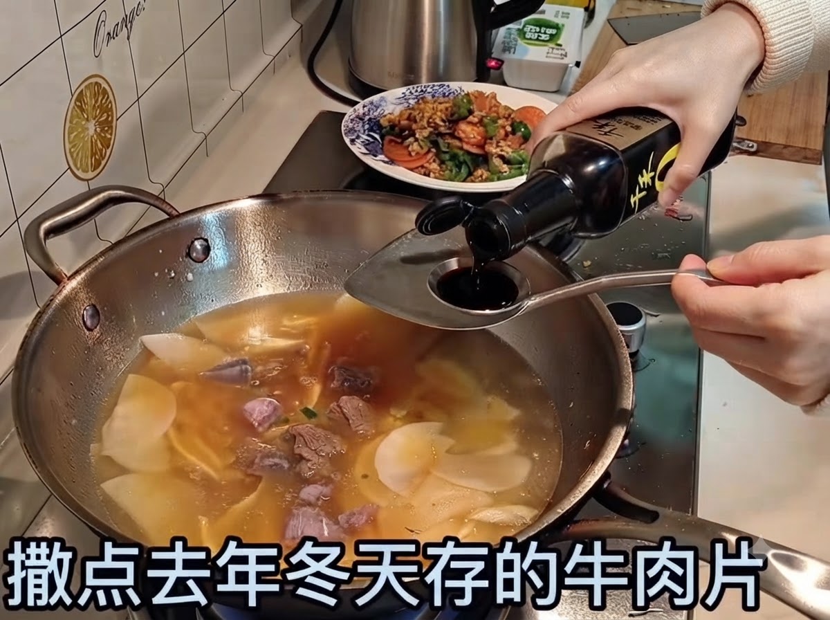 De la sauce soja versée dans un bouillon frémissant contenant des tranches de bœuf et des légumes.
