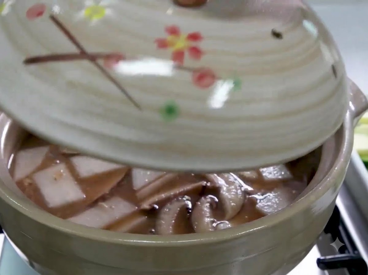 Une main posant un couvercle sur la marmite en céramique remplie de bouillon, de radis et de champignons.