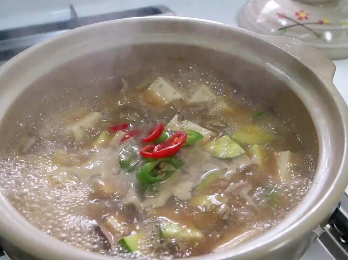 Des piments rouges et verts émincés ainsi que des oignons verts mijotant dans une marmite de Doenjang Jjigae.