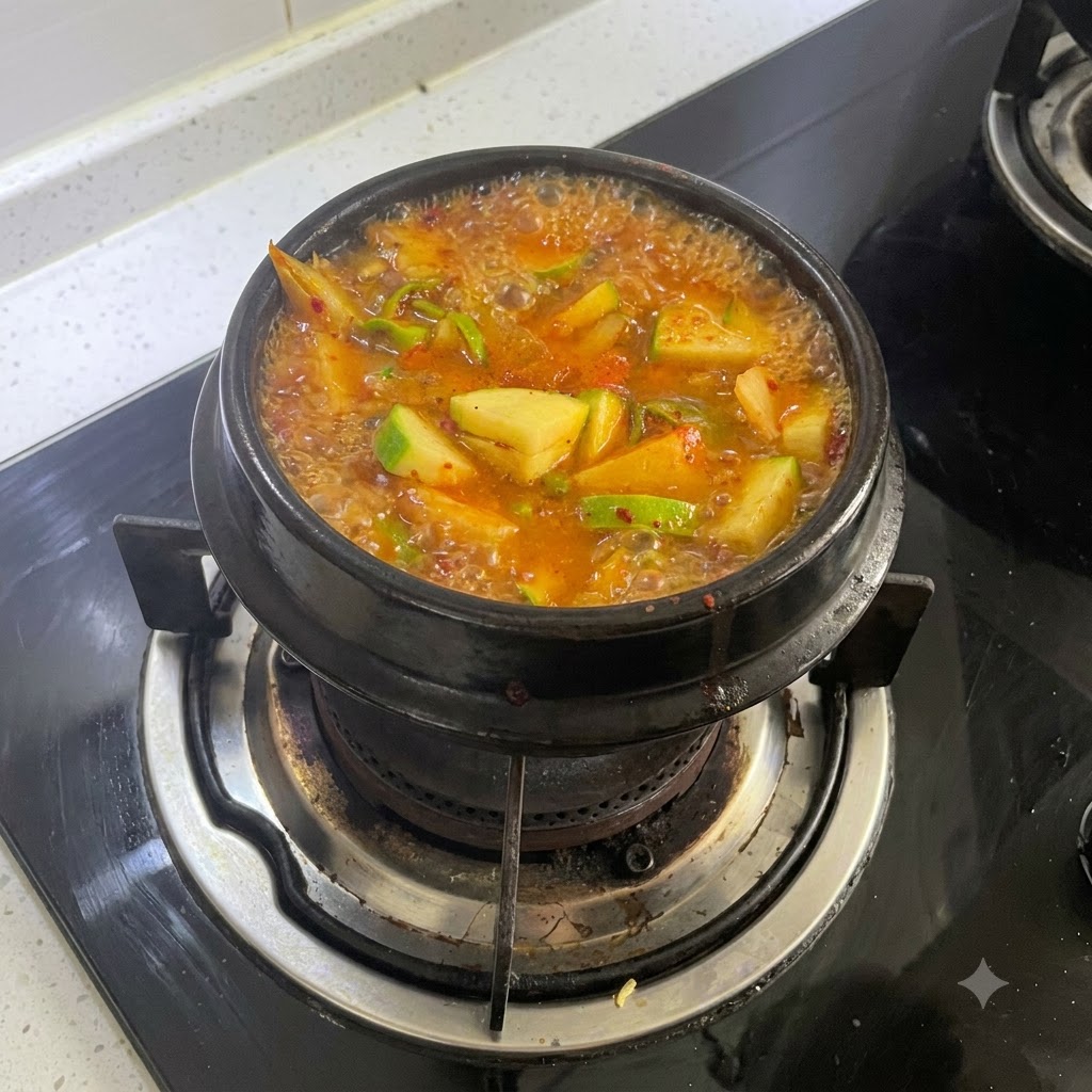 Une casserole bouillante de ragoût orange-rouge vif mijotant sur un feu de cuisinière à gaz.