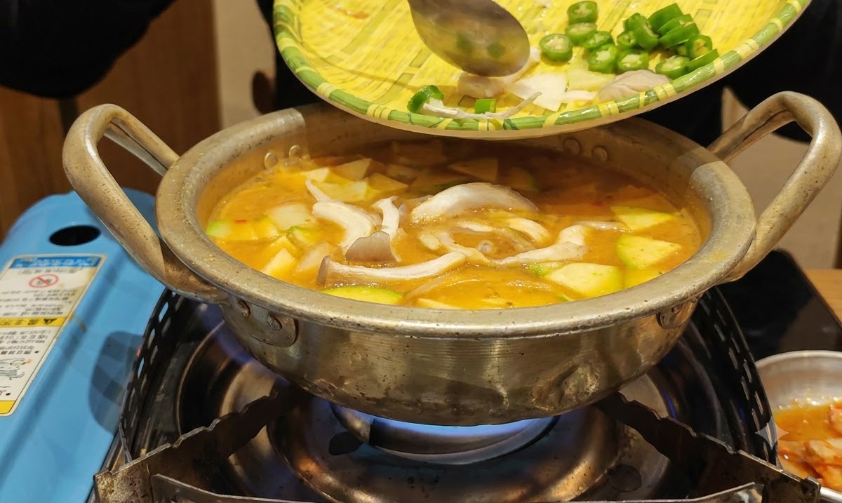 Des légumes préparés glissant dun plateau en osier dans la casserole de ragoût bouillante.