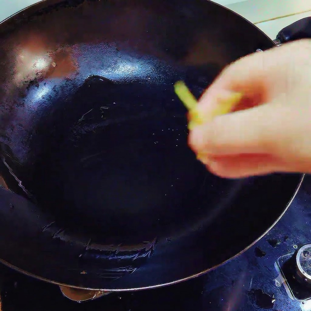 Morceaux de gingembre et dail jetés dans un wok contenant du saindoux fondu sur le feu.