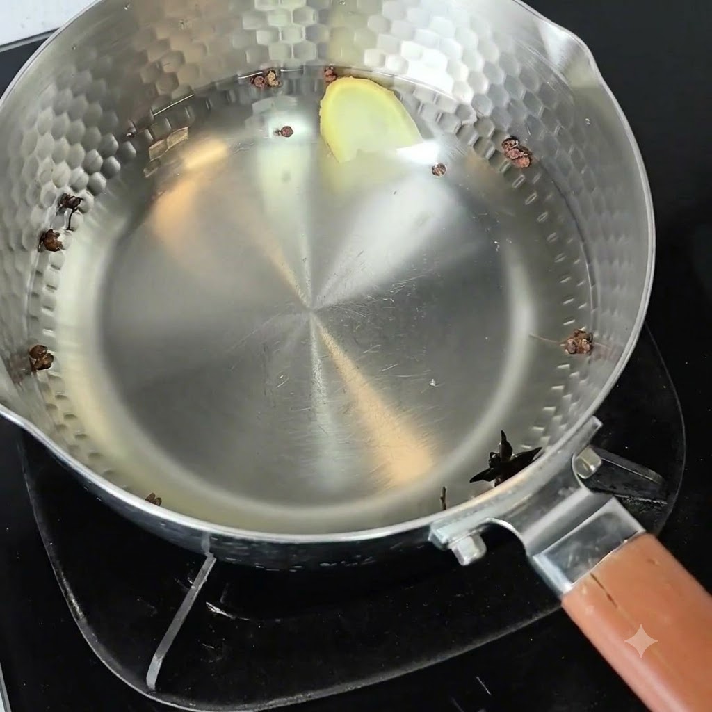 Une casserole en métal remplie deau froide, de grains de poivre du Sichuan, de badiane et dune tranche de gingembre sur un feu.