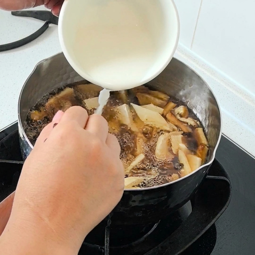 De lamidon deau versé dun bol blanc dans une casserole de soupe bouillonnante.