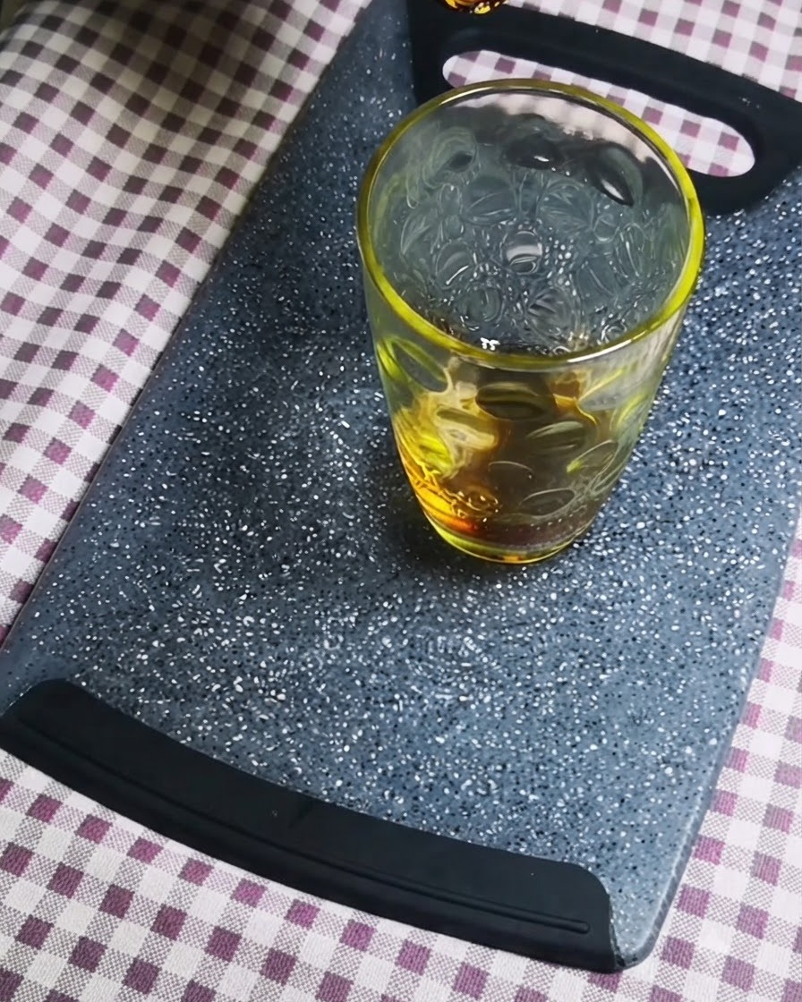 De la sauce soja foncée versée dans un récipient en verre transparent sur une planche à découper grise.