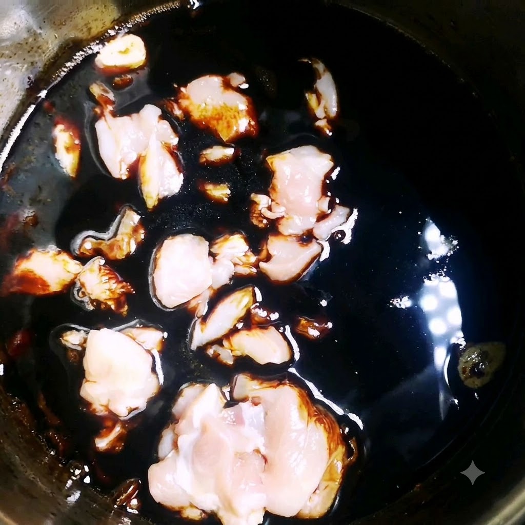Des morceaux de poulet cru mijotant dans une sauce foncée et savoureuse à lintérieur dune casserole.