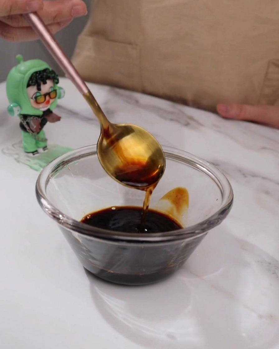 Ingrédients de la sauce teriyaki mélangés dans un petit bol en verre avec une cuillère.