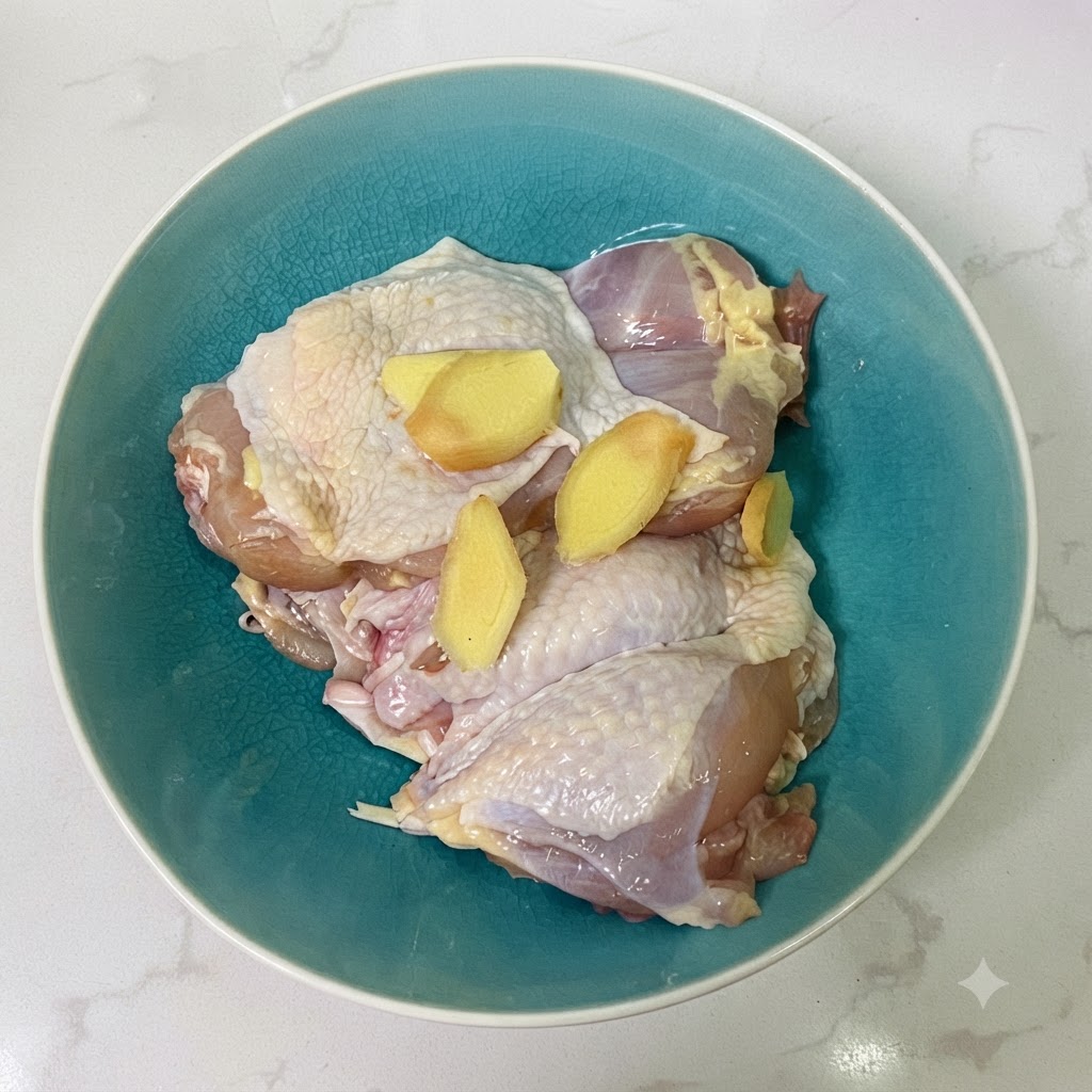 Cuisses de poulet et tranches de gingembre dans un bol en céramique bleue avec de la sauce soja.