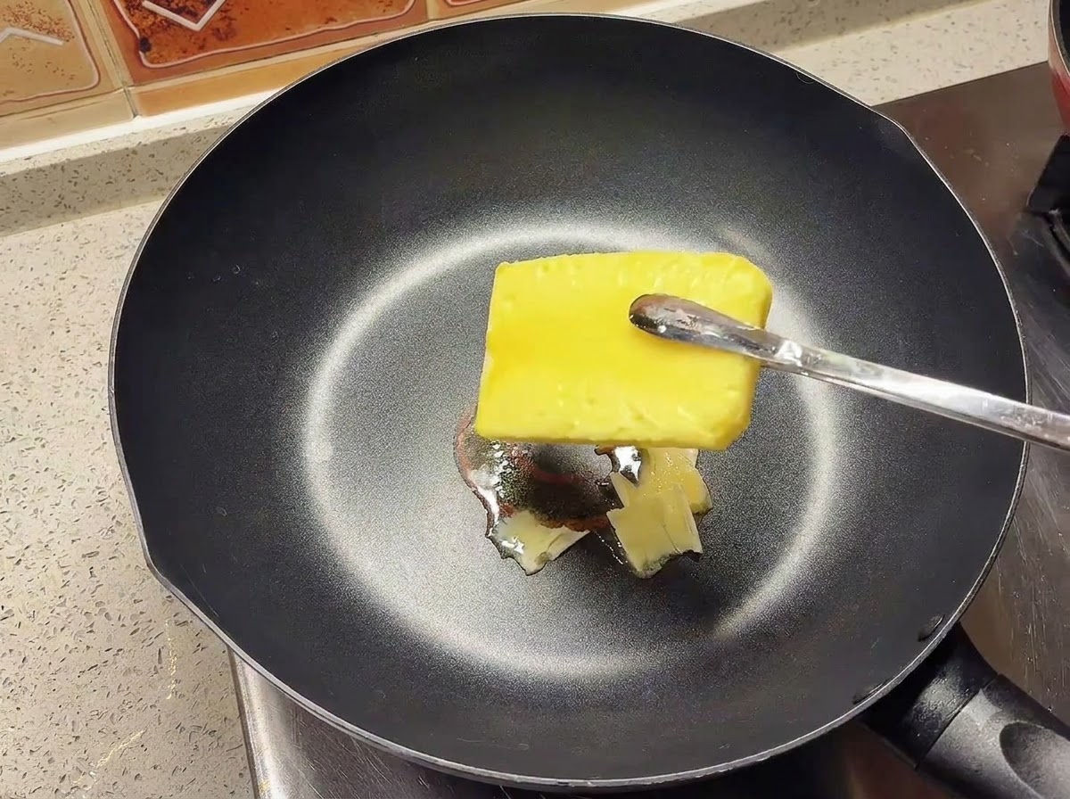 Un morceau de beurre fondant dans une poêle noire bien chaude.