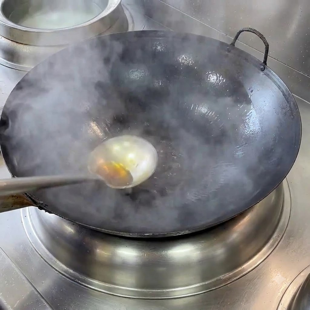 Un wok en fonte fumant sur une gazinière, avec une louche et de lhuile chaude.