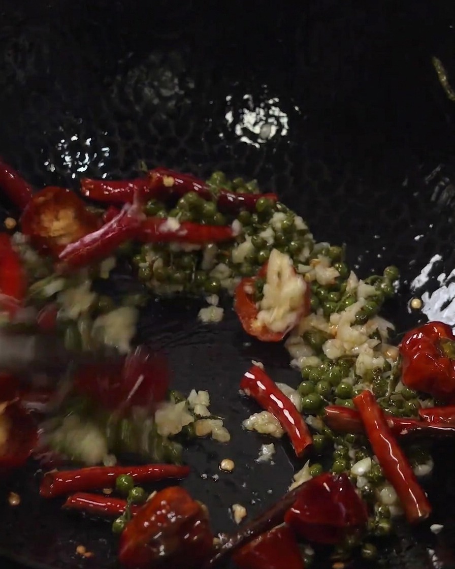 Travers de porc frits et aromates mélangés ensemble dans un wok.