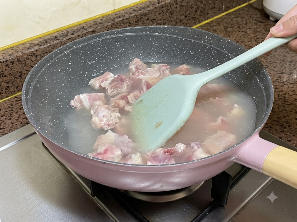 Travers de porc bouillant dans leau à lintérieur dune casserole tout en étant remués avec une spatule en silicone bleu clair.