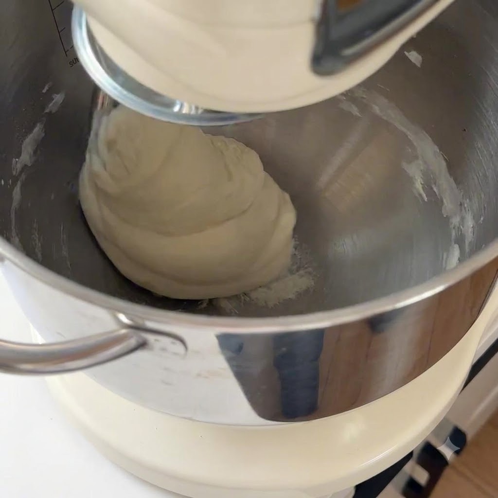 Pâte à pizza lisse pétrie dans le bol dun robot pâtissier.