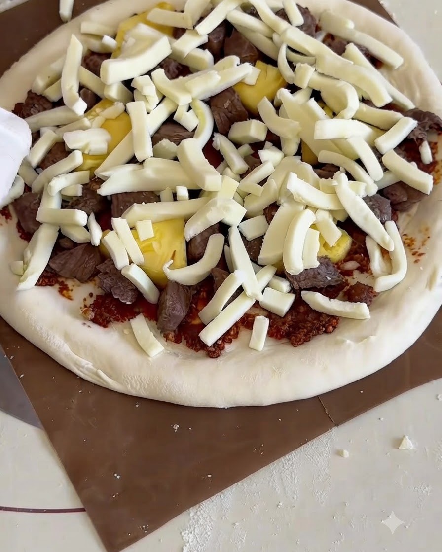 Pizza crue garnie sur une pelle en bois glissée dans un petit four à pizza.