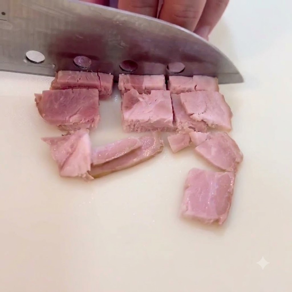 Tranches de bacon coupées en petits carrés sur une surface de découpe.