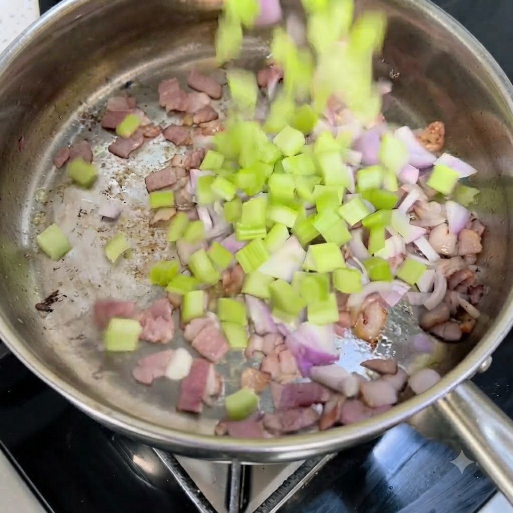Céleri et oignons rouges coupés en dés tombant dans une poêle chaude avec des morceaux de bacon croustillants.