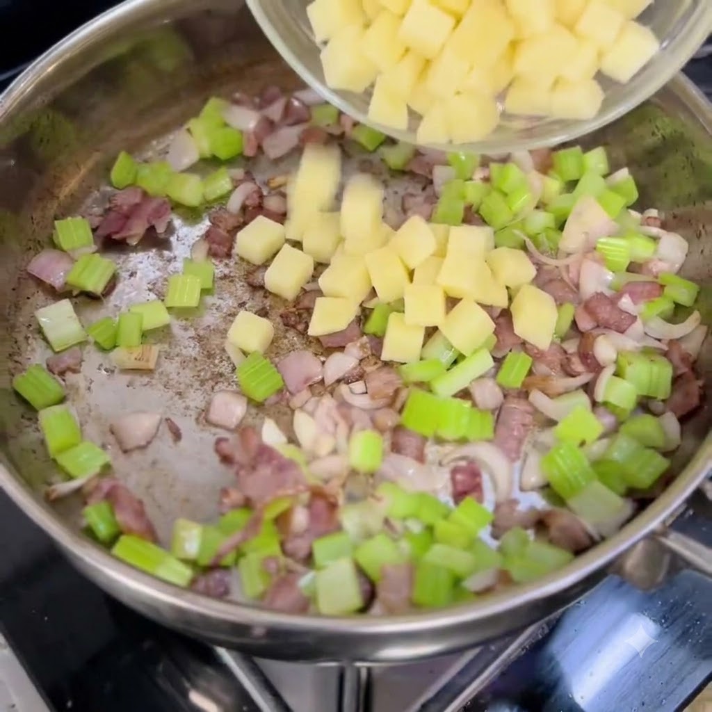 Pommes de terre en dés versées dun bol transparent dans une poêle contenant des oignons hachés, du céleri et du bacon.