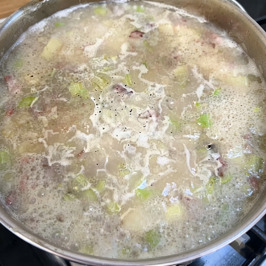 Une casserole de base de chowder mijotant avec du poivre noir parsemé sur la surface bouillonnante.