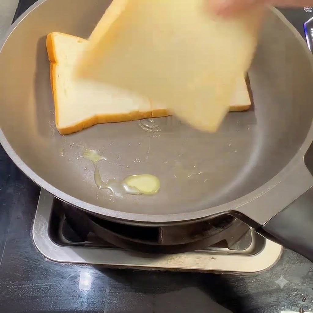 Trois tranches de pain de mie blanc placées dans une poêle beurrée.