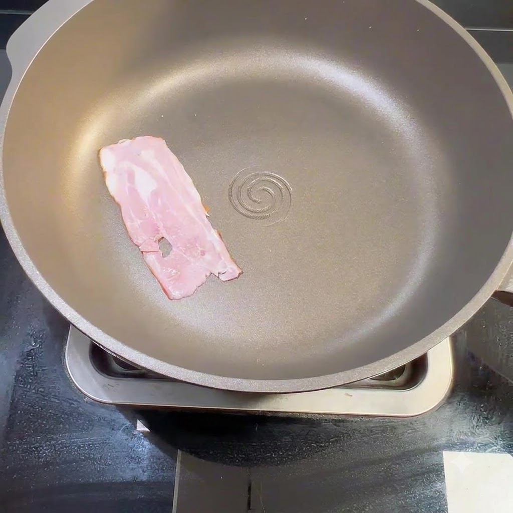Une lanière de bacon cru placée à plat à lintérieur dune poêle sèche sur la cuisinière.