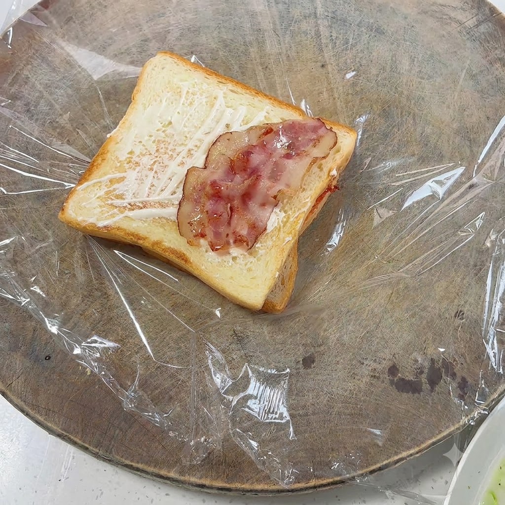 Des morceaux de bacon cuit disposés sur le dessus du pain toasté.