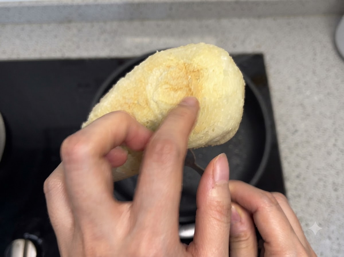 Une main appuyant sur la surface inférieure dun morceau de pain toasté pour vérifier son croustillant.