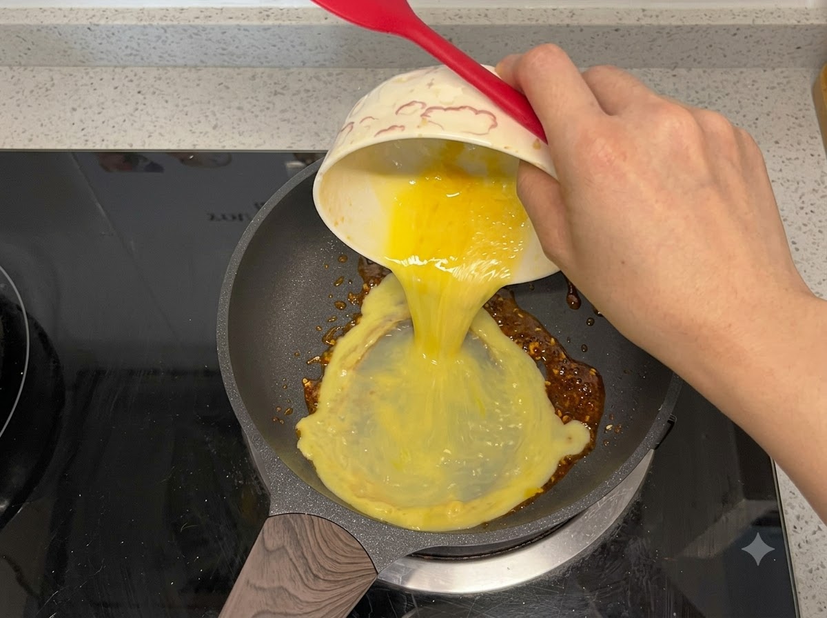 Des œufs battus versés dans une poêle à frire avec de lhuile pimentée.